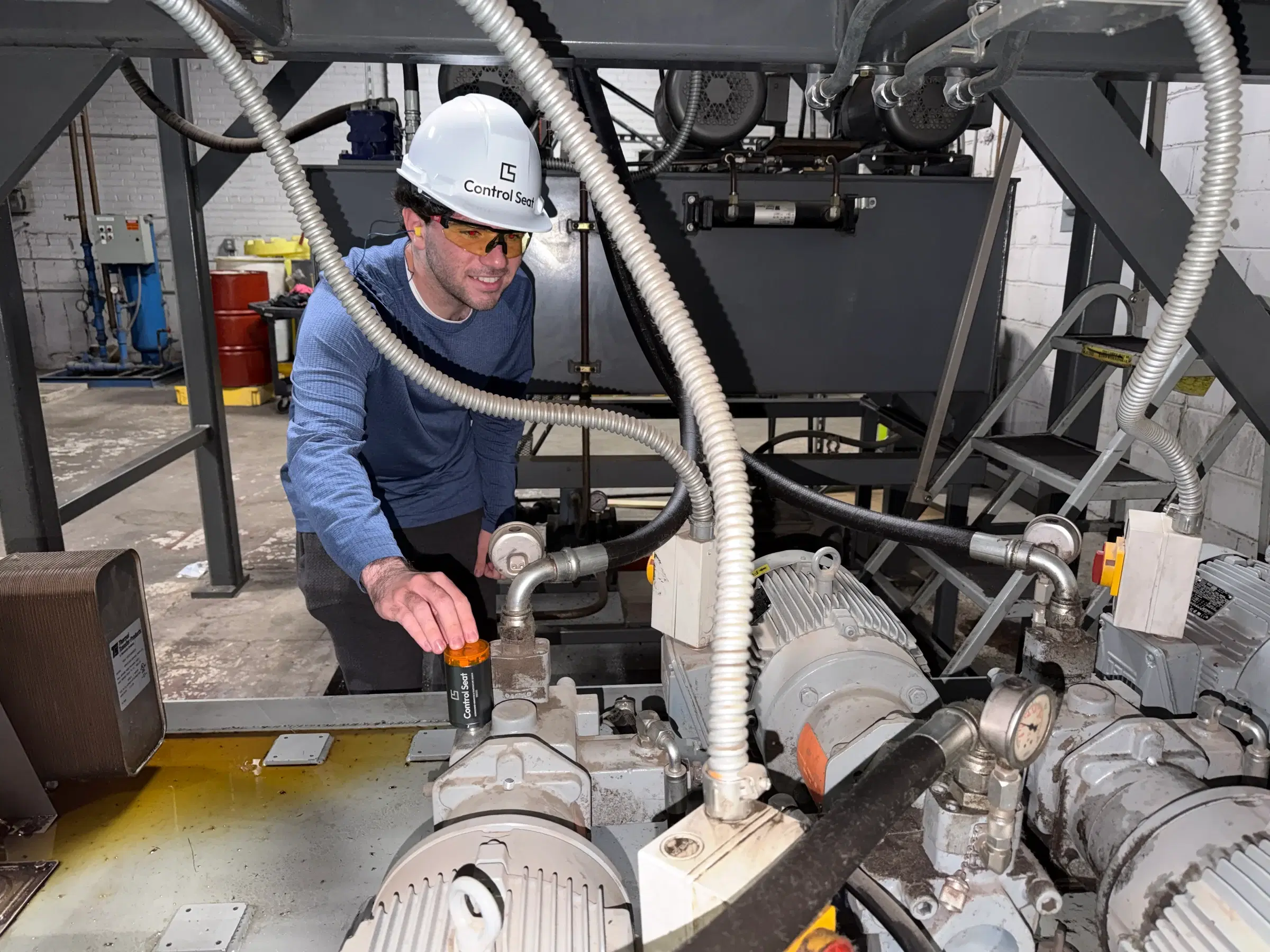 A Control Seat co-founder installing a wireless sensor on factory equipment